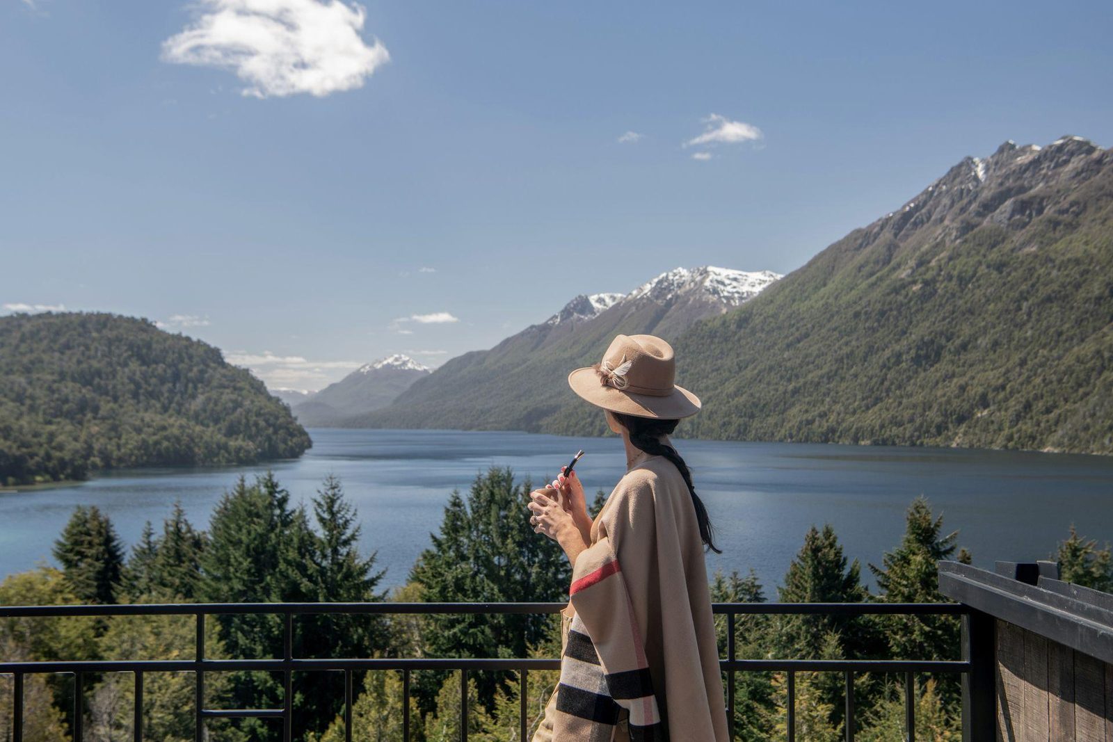 Mujer contemplando un paisaje de montañas y lago, con serenidad y amplitud